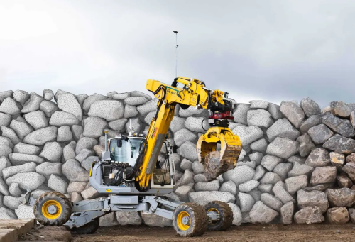 HEAP excavator in front of a recently constructed stone wall.