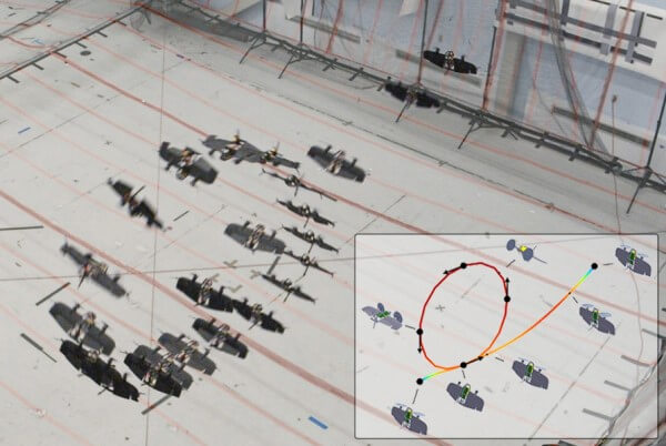 Tailsitter drones positioned on a grid-marked floor with an overlay shows a simulated flight path, marked by a circular trajectory with directional arrows.